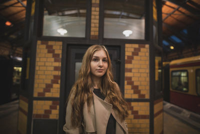 Portrait of young woman standing by railroad station