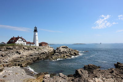 Lighthouse by sea against sky