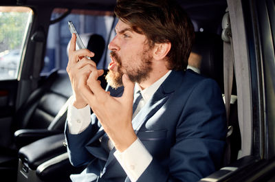 Frustrated businessman talking on phone while sitting in car