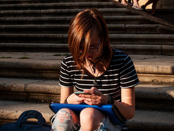 Teenage girl using mobile phone while sitting on steps