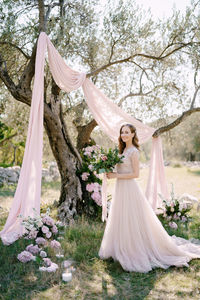 Woman with umbrella standing by flower tree