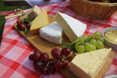 High angle view of cheese slices and grapes on cutting board