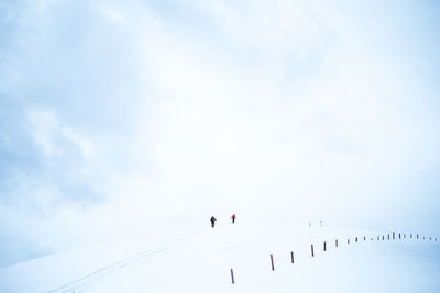 Low angle view of people on snow against sky