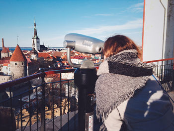 Woman looking through coin-operated binoculars in city