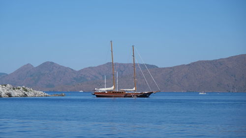 Sailboat sailing on sea against clear blue sky