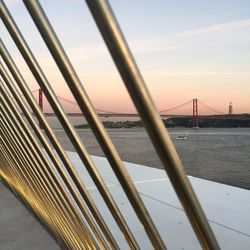 View of bridge over calm sea at sunset