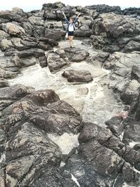 Low section of woman standing on rock by sea