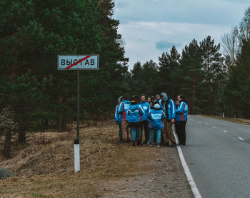 Rear view of people walking on road against trees