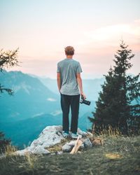 Rear view of man standing on mountain against sky