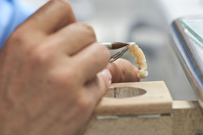 Close-up of dentist using paintbrush on artificial teeth