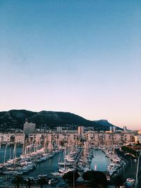 Sailboats moored in city against clear sky