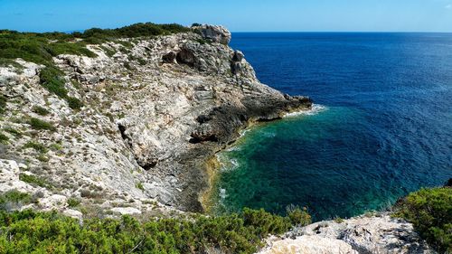 Rock formations by sea against blue sky