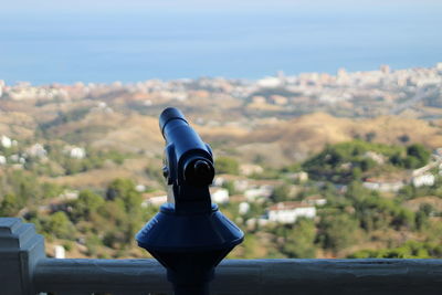 Close-up of coin-operated binoculars against cityscape