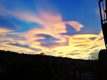 Silhouette houses and trees against sky at sunset