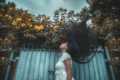 Woman standing by tree against plants