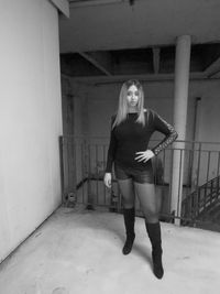 Portrait of young woman standing against building