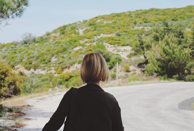 Rear view of woman walking on mountain road