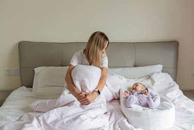 Mother and daughter lying on bed at home