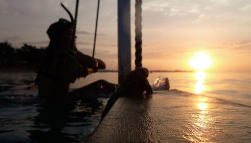 Silhouette people on beach against sky during sunset