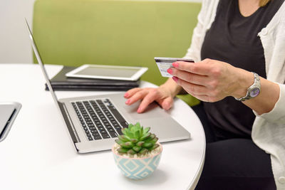 Midsection of woman using laptop on table