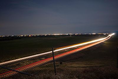Light trails on road against sky at night