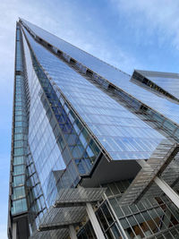 Low angle view of modern glass building against sky