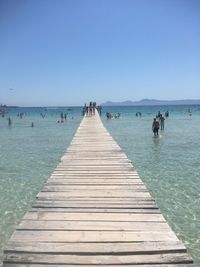 Pier over sea against clear blue sky