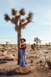 Full length of mid adult woman standing by tree against sky