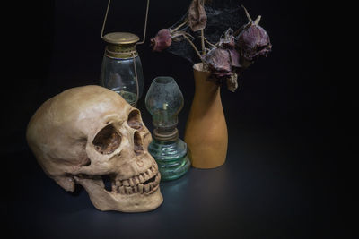 High angle view of skull and vase with lantern on black background