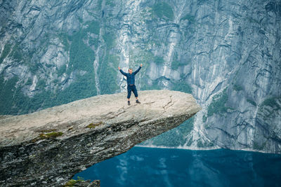Man standing on cliff over lake