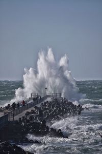 Waves splashing on sea against clear sky