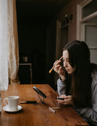 Side view of young woman using mobile phone at home