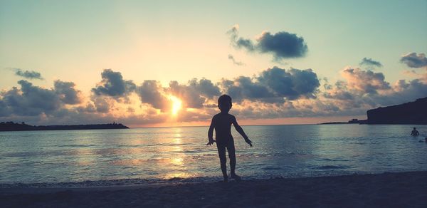 Silhouette man standing on beach against sky during sunset