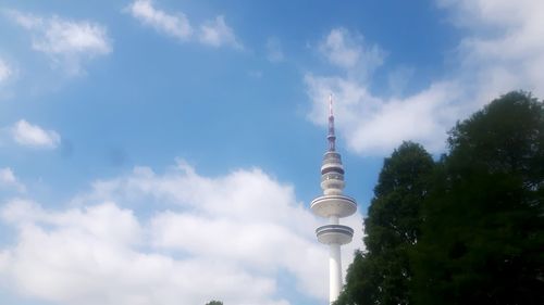 Low angle view of communications tower against cloudy sky