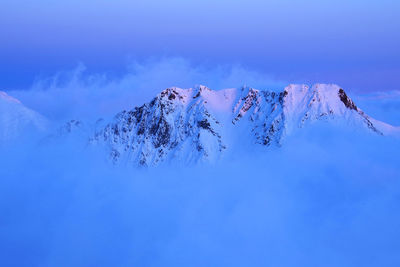 Scenic view of snow covered mountain against blue sky