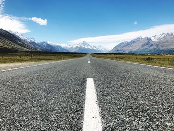 Surface level of road by mountains against sky