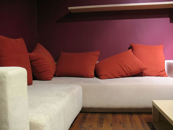 Purple wall living room with modern light beige sofa and five red pillows