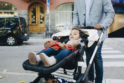 Father pushing daughter in carriage on street at city