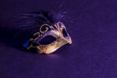 High angle view of venetian mask on purple background