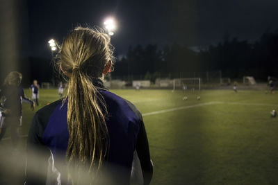 Side view of girl seen through goal post net on soccer field