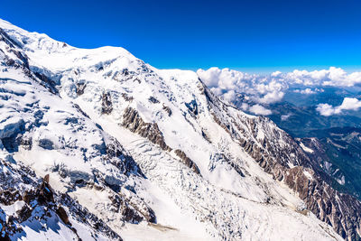 Scenic view of snowcapped mountains against blue sky