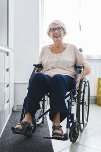 Happy disabled senior woman sitting on wheelchair at home