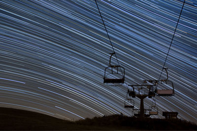 Low angle view of overhead cable car against sky at night