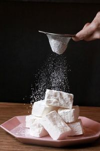 Close-up of hand holding ice cream on table against black background