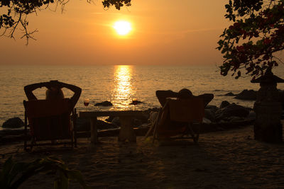 Two people overlooking calm sea at sunset