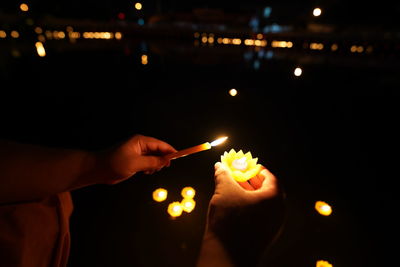 Close-up of hand holding lit candles