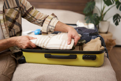 Midsection of man holding suitcase