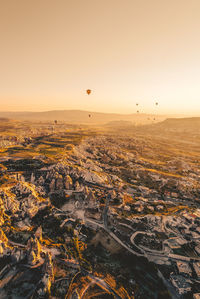 Hot air balloons flying over landscape at cappadocia during sunset