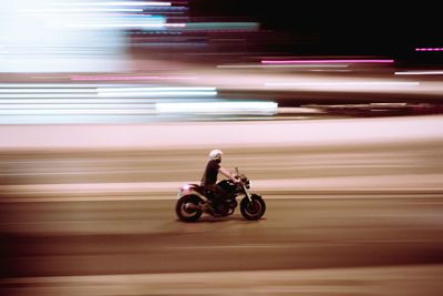 Blurred motion of man riding motorcycle on road at night