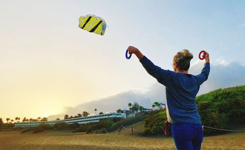 Rear view of woman flying kite on field